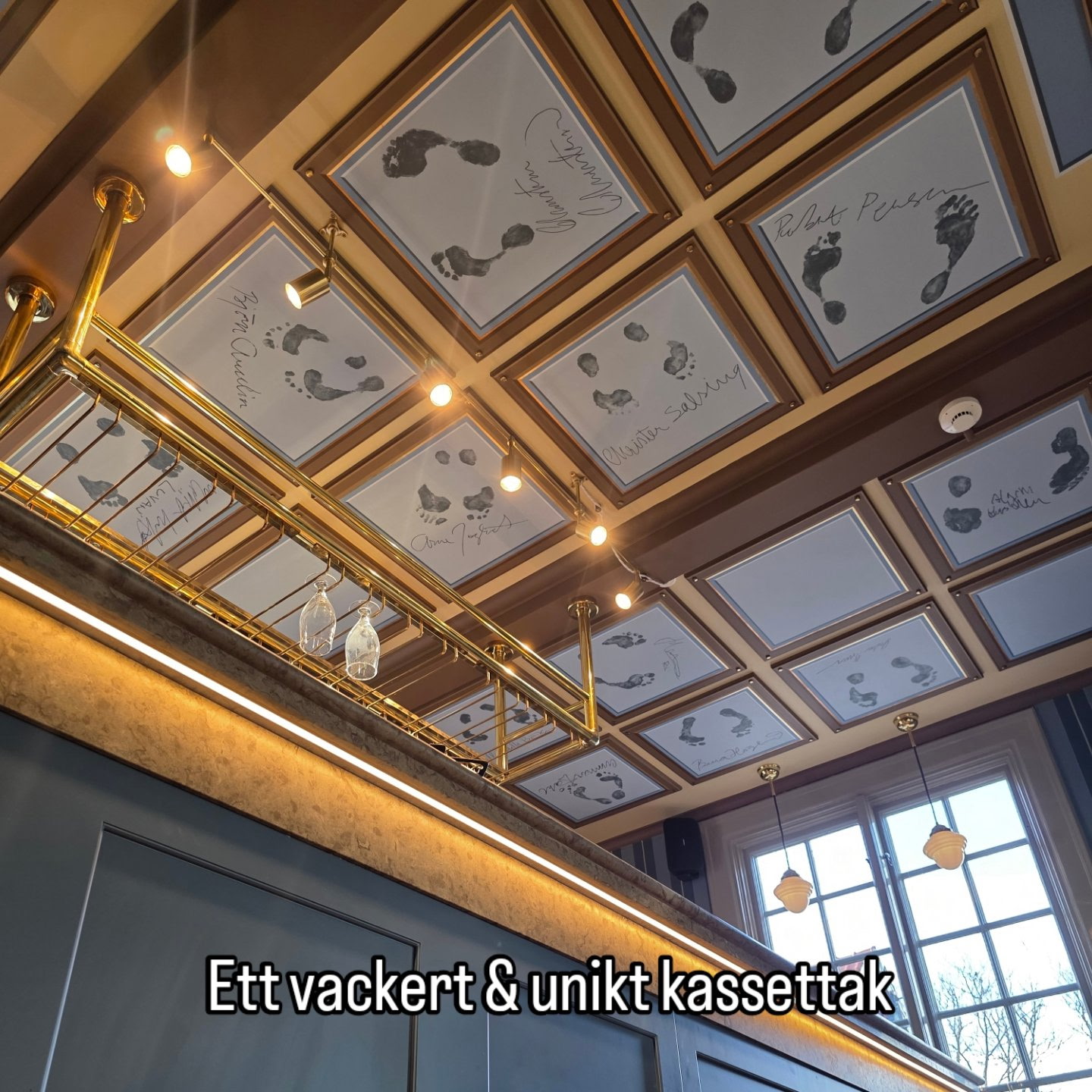 Förgyllt kassettak med handmålade fotavtryck ovanför en bar